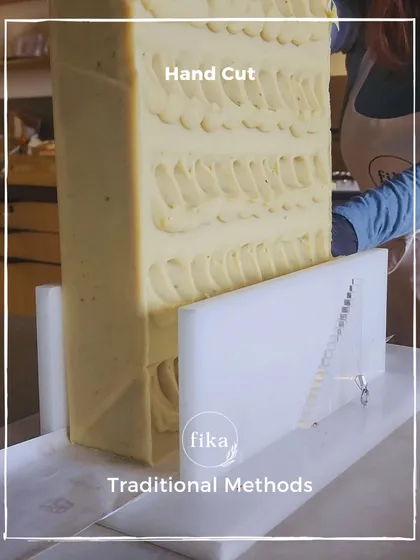I use traditional methods to create my products. This large, textured soap loaf is being positioned in a single-wire cutter, a simple tool that allows for a clean, precise slice every time.