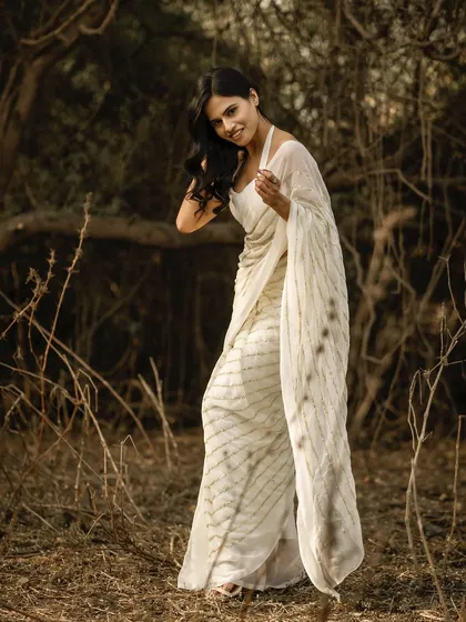 I love using the rustic landscapes around Mumbai to create soft, natural fashion portraits. This image, shot in a wooded area, uses the warm, diffused sunlight to create a gentle, ethereal mood that complements the flowing white saree. It’s a great example of a lifestyle fashion shoot.