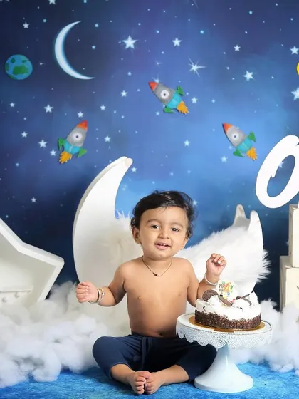 Before the cake comes out, we capture some clean portraits. This little one is ready for his space-themed first birthday celebration, sitting in front of a moon and stars backdrop.