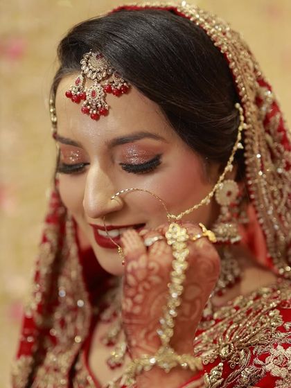 A happy and smiling bride on her Nikkah day. Her makeup is classic and radiant, with glittery eyes and a beautiful red lip.