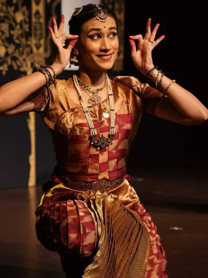 A playful and expressive moment on stage, using hand gestures (mudras) and facial expressions to portray a specific character or emotion.