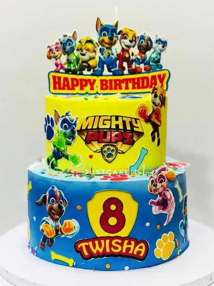A vibrant two-tier Mighty Pups theme cake. The bright yellow and blue colors and action-packed characters make this a very dynamic design.
