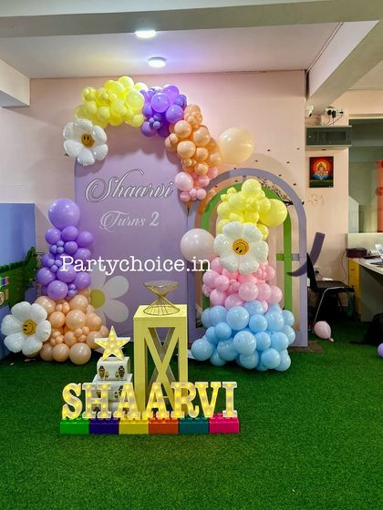 A sweet flower garden theme for a second birthday. The decoration includes pastel-colored balloon arrangements and large daisy flower balloon accents.