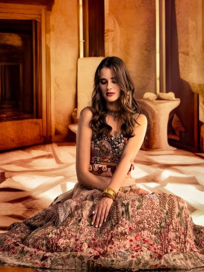 An abstract, sandy-toned environment is projected to create a minimalist yet intriguing setting. The focus is on the model's pose and the beautiful floral patterns of her dress.