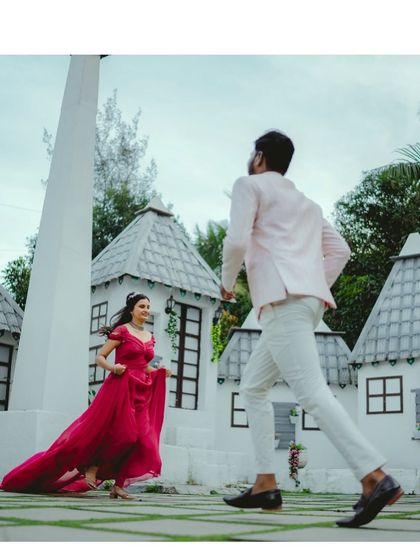 A playful and dynamic pre-wedding shot. The movement in this photo captures the couple's happy energy, with the bride in a flowing magenta gown.