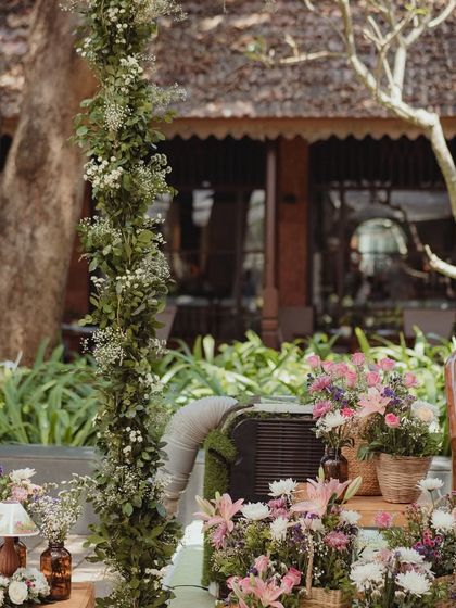 A view of the Mehendi stage decor, showing the lush floral arrangements and the tall, delicate green arches.