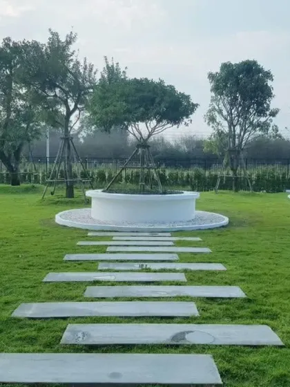 A minimalist pathway of stone slabs leads across a wide lawn to a circular feature. This design uses negative space effectively, creating a sense of calm and openness.
