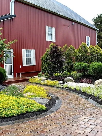 A good walkway should be more than just practical. For this home, I built a winding paver path that makes the walk to the barn a beautiful part of the property, surrounded by plants that will fill in nicely over time.
