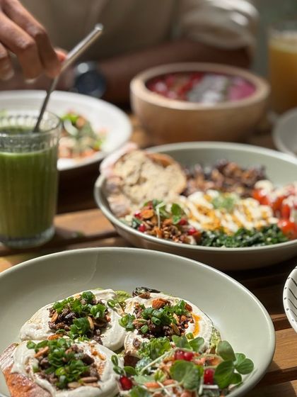 A table full of our nourishing dishes. From colorful bowls to fresh juices, it is all about food that makes you feel good.