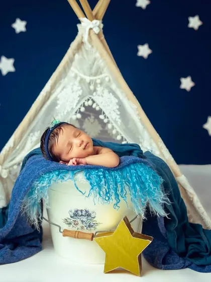 The full starry night scene, showing the baby asleep in a bucket prop against a deep blue, star-filled background with a lace teepee.