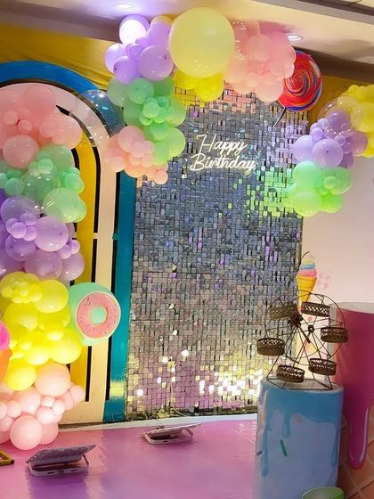 A sweet ice cream and candy themed party. This decoration features pastel balloon clouds, a shimmer wall, and large ice cream cone props.