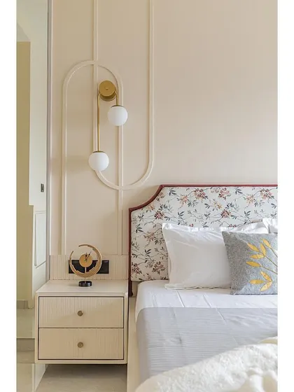 A close-up of the unique, modern pendant light and the custom-designed bedside table. The wall moulding adds a subtle architectural detail.