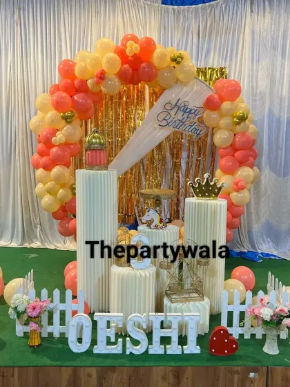 A beautiful ring decoration with peach and orange balloons against a white curtain. The gold shimmer curtain in the center adds a touch of glamour.