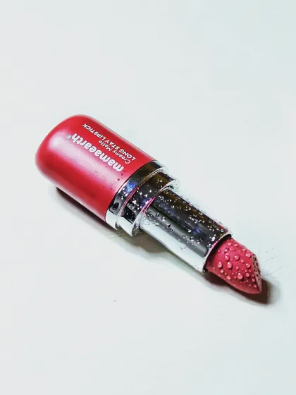 A minimalist shot of a single Mamaearth lipstick on a clean white surface, emphasizing its sleek packaging and color.
