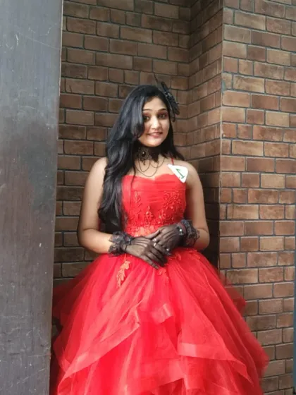 Our red ball gown is a popular choice for events and photoshoots. This client looks stunning posing against a brick wall, showing the dress's versatility.