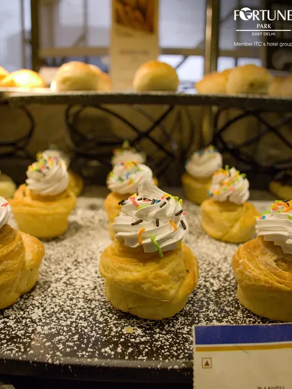 A close-up of our mini cruffins topped with whipped cream and sprinkles, a delightful treat from our pastry section.