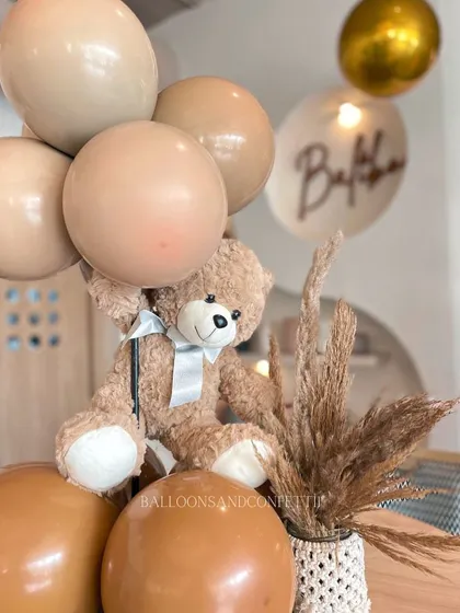 Adorable teddy bear table centerpieces, with the teddy holding a small bunch of neutral-colored balloons. These little details tie the whole theme together.