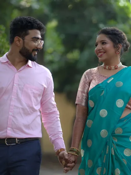 A happy couple walking hand-in-hand after their engagement pooja. The bride's makeup is soft and natural, perfect for a daytime event.