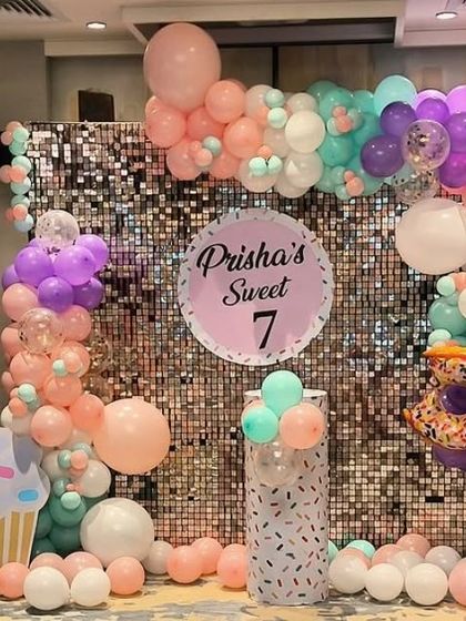 A "Sweet 7" party with a donut and cupcake theme, a sequin wall, and pastel-colored balloons.