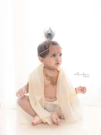 A contemplative moment. The simple styling and clean background allow the baby's sweet expression and posture to be the main focus of the photograph.