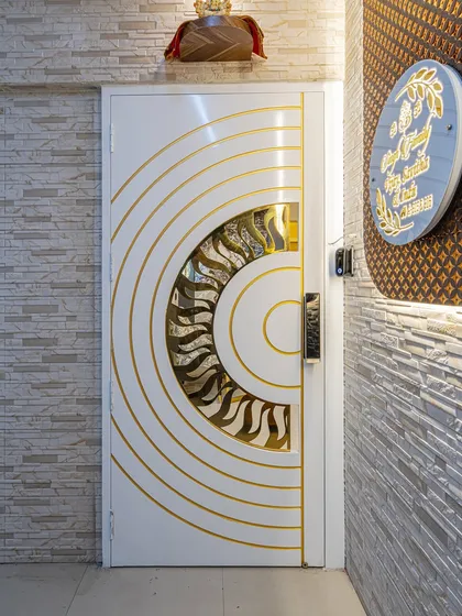 Your main door is the first thing people see. I designed this custom safety door with a white Duco paint finish and a PVD coated jaali, matching the inner door's pattern to create a grand and cohesive entrance.