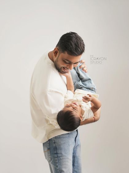 A moment of playful fun, captured forever. A father holds his son upside down, and the resulting laughter makes for a wonderfully authentic and joyful studio portrait.