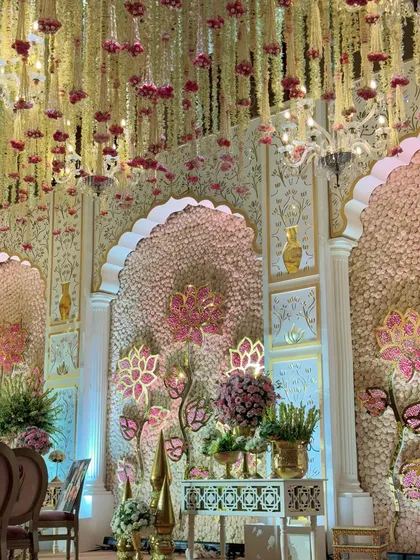 A view of the mandap through the cascading floral ceiling. The layers of decor, from the flowers above to the detailed backdrop, create a sense of immersive beauty.