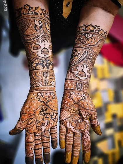 A beautiful example of symmetrical bridal mehendi. Both hands mirror each other with peacock and jhumka motifs, creating a balanced and harmonious design that extends up the arms.