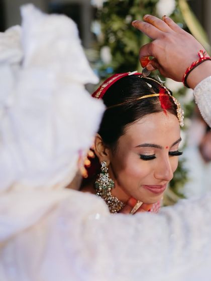 A sacred moment from the wedding ceremony. The bride's makeup is soft and reverent, perfect for the solemnity of the pheras.