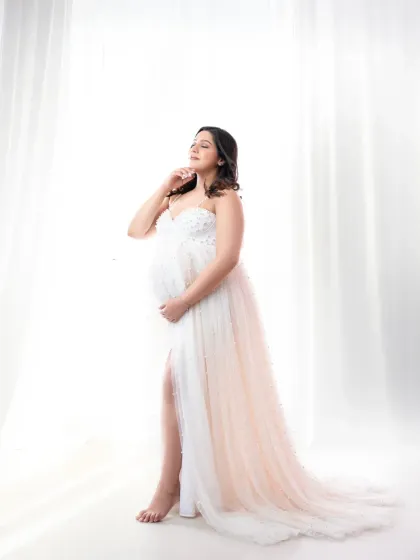 Bathed in soft, natural light. This high-key portrait in a delicate white gown creates a dreamy and serene mood, highlighting the peaceful side of pregnancy.