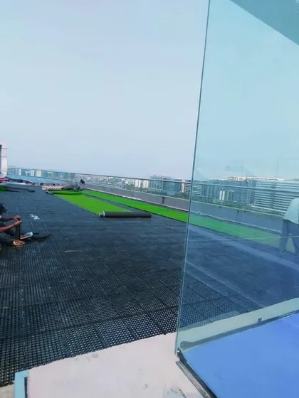 This image shows the scale of a rooftop project, with a large area covered in drainage cells before the final surface, like artificial grass, is installed.