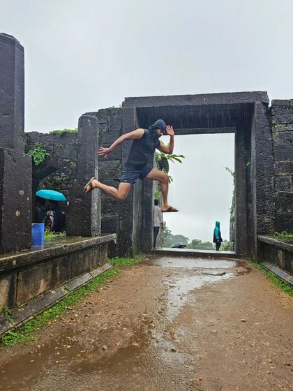 A trekker takes a joyful leap at the entrance of Kavaledurga Fort, capturing the fun spirit of our trips.