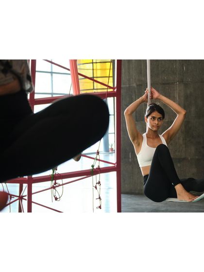 A student sits gracefully in the hammock, a moment of rest and contemplation during a fulfilling aerial yoga session.