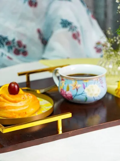 A cozy lifestyle shot of a coffee and pastry on a tray, set for a relaxing morning.