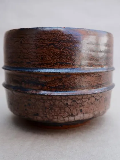 Another view of the Raku teabowl, showing the fine network of cracks and the subtle variations in the brown, earthy glaze.