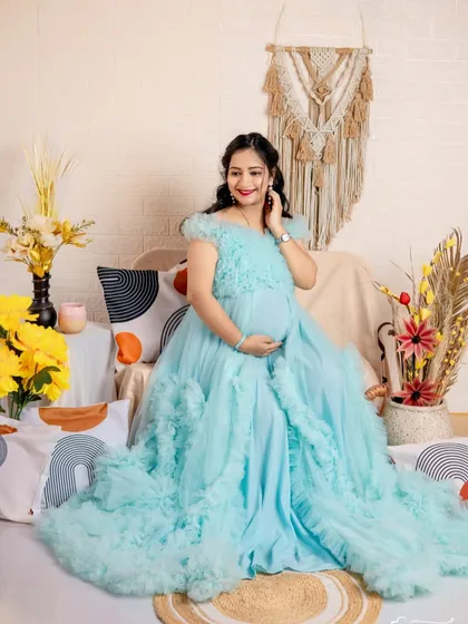 Feel like a princess in this light blue ruffled maternity gown. The voluminous skirt and delicate details are perfect for a whimsical indoor studio shoot.