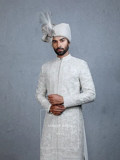 Grace woven in ivory. A sherwani embellished with fine thread embroidery and tiny beads, styled with a pleated stole and a minimal turban with a sarpech, personifying timeless royalty.