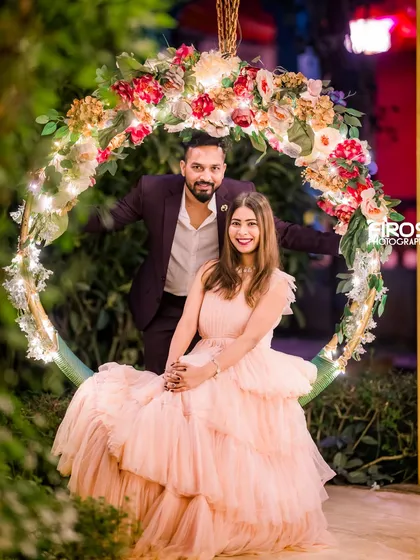 A joyful portrait on the floral swing, where the night lights add a touch of magic to the couple's pre-wedding celebration.