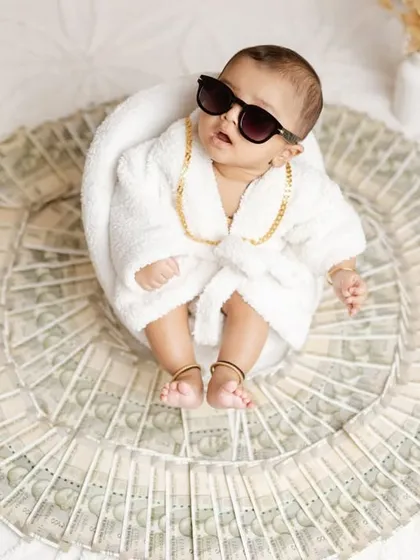 The ultimate boss baby. This fun and creative 'Royal Karbhar' (royal affair) theme features a baby in a bathrobe lying on a bed of money.