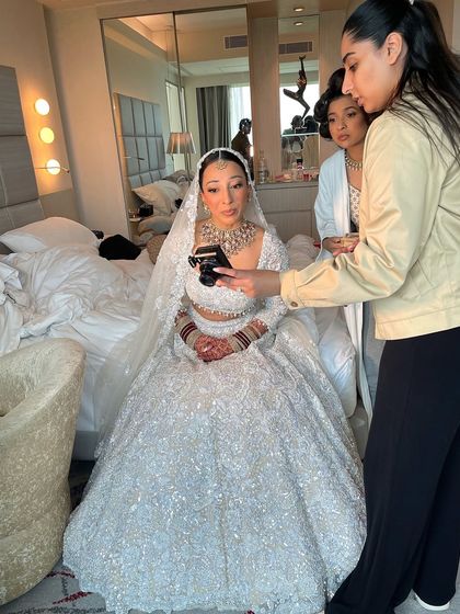 A candid moment during the getting ready process. Here you can see the sleek bun holding up perfectly as the makeup artist and photographer capture the final look.