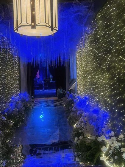 Another perspective of the celestial entrance walkway. The deep blue lighting on the floor and ceiling contrasts beautifully with the warm, star-like fairy lights on the walls, guiding guests through a magical passage.