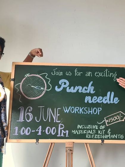 Two happy crafters posing with our workshop announcement board and their finished pieces.