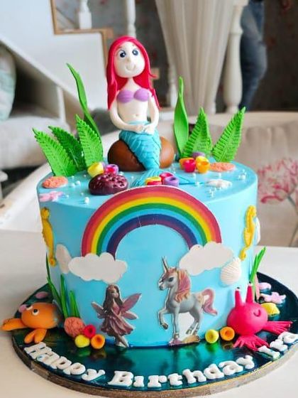 A magical mermaid and unicorn cake, combining two fantasy worlds with a rainbow, seahorses, and underwater elements.