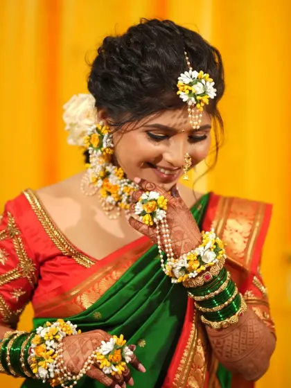 A vibrant Haldi look with a green and red saree, adorned with beautiful fresh floral jewellery.