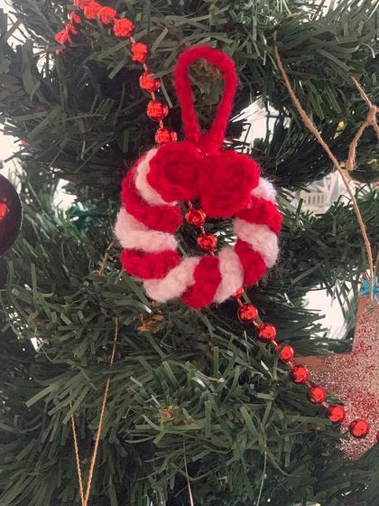 A candy cane wreath ornament hanging on a Christmas tree. It's a small detail that adds a lot of charm.