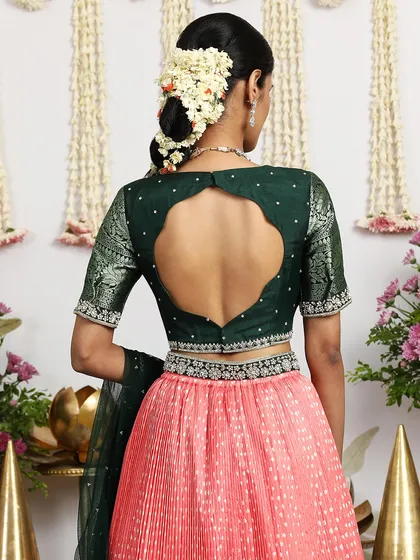 The back view of the deep green blouse paired with the coral pink lehenga, showcasing the beautiful contrast.