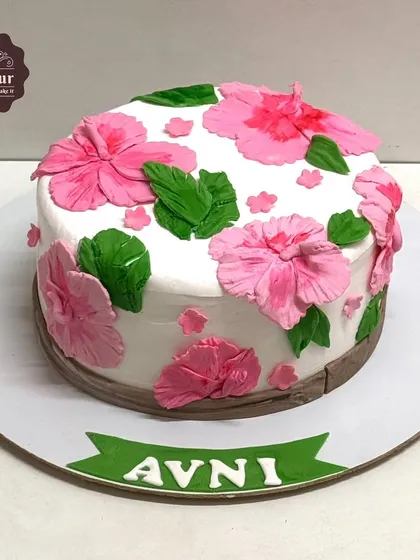 A simple and pretty vanilla truffle cake decorated with hand-crafted pink hibiscus flowers. This shows how a few delicate details can make a cake beautiful.
