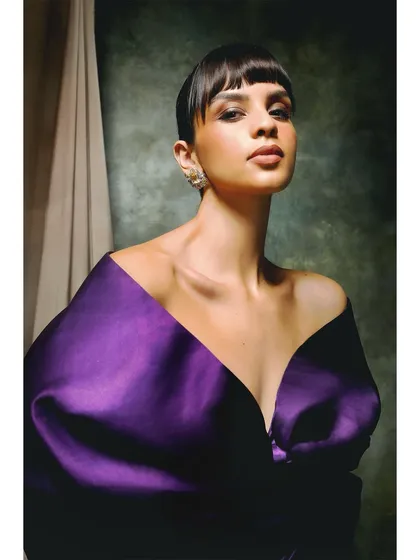 A bold portrait for Ambika Lal, featuring a striking purple off-shoulder top. The clean, direct styling and the model's confident gaze make for a powerful and modern fashion image.