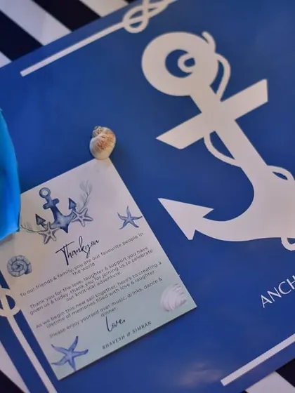 A custom 'Anchored in Love' place mat and thank you card for the nautical-themed engagement. These personalized paper goods made each guest feel special and added to the cohesive theme.