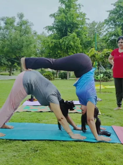 Partner yoga in the park is a beautiful way to connect with another person and with nature. This Acro Yoga pose, a supported downward dog and handstand variation, builds strength, balance, and a great deal of trust between partners.